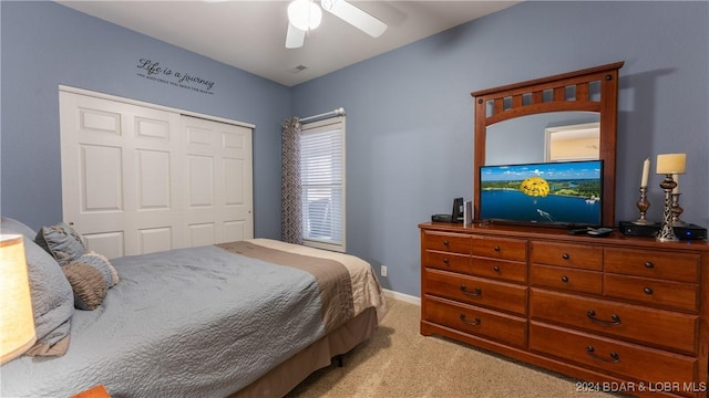 bedroom featuring light colored carpet, a closet, and ceiling fan