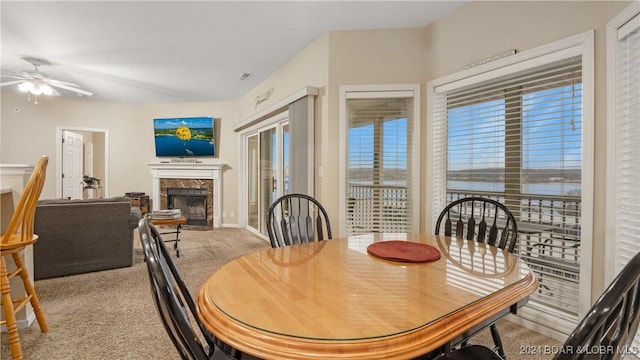 dining space featuring a healthy amount of sunlight, a premium fireplace, ceiling fan, and light carpet