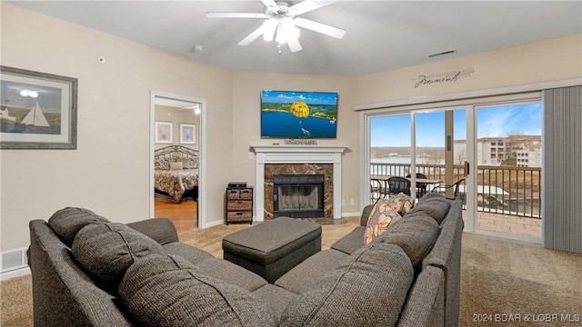 living room featuring ceiling fan, a fireplace, and light colored carpet