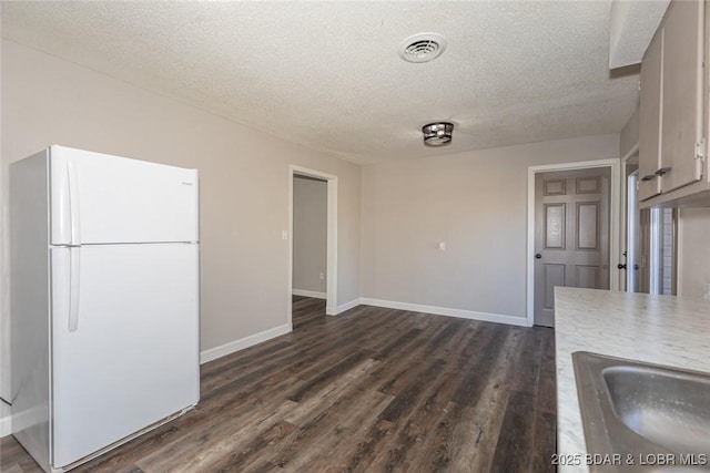 unfurnished dining area featuring a textured ceiling and dark wood-type flooring