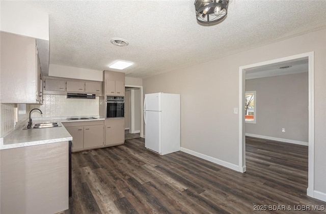 kitchen with sink, gas stovetop, oven, white fridge, and a textured ceiling