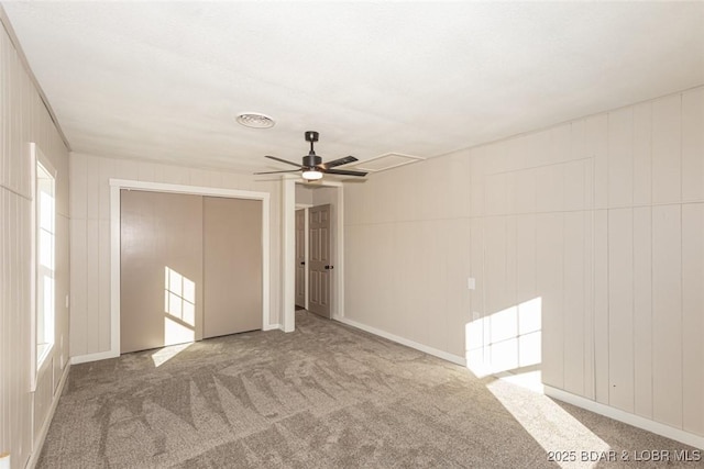 carpeted empty room with ceiling fan and wood walls