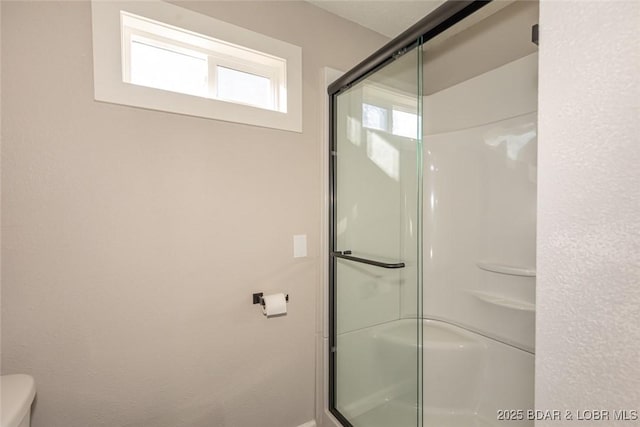 bathroom featuring toilet and an enclosed shower