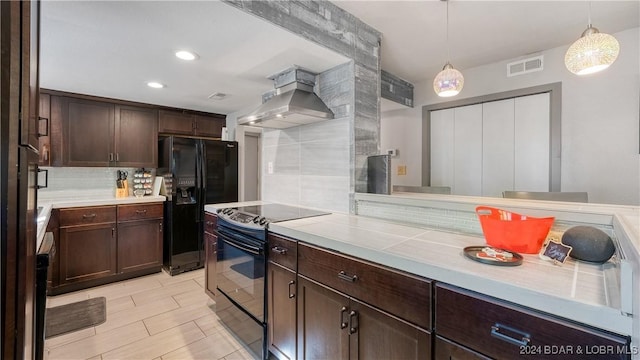 kitchen with black appliances, hanging light fixtures, wall chimney exhaust hood, tasteful backsplash, and dark brown cabinets