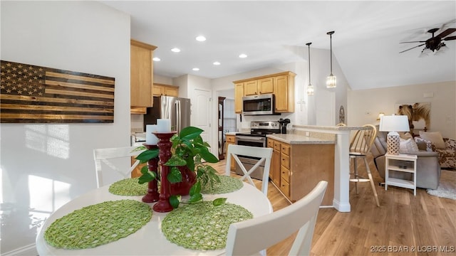 dining room featuring ceiling fan, light wood-type flooring, and lofted ceiling