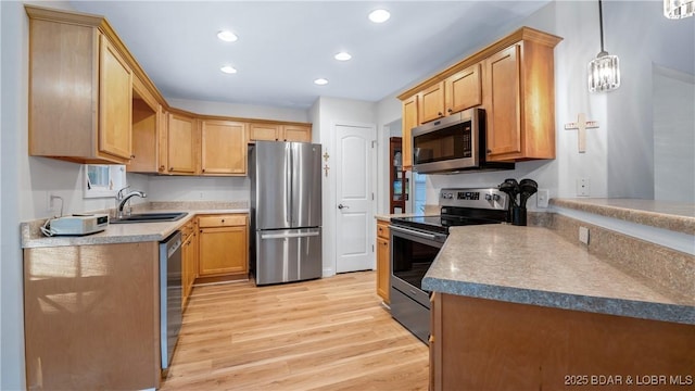 kitchen featuring sink, light hardwood / wood-style flooring, hanging light fixtures, and appliances with stainless steel finishes