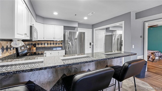 kitchen with backsplash, kitchen peninsula, stainless steel refrigerator, high end fridge, and a breakfast bar area