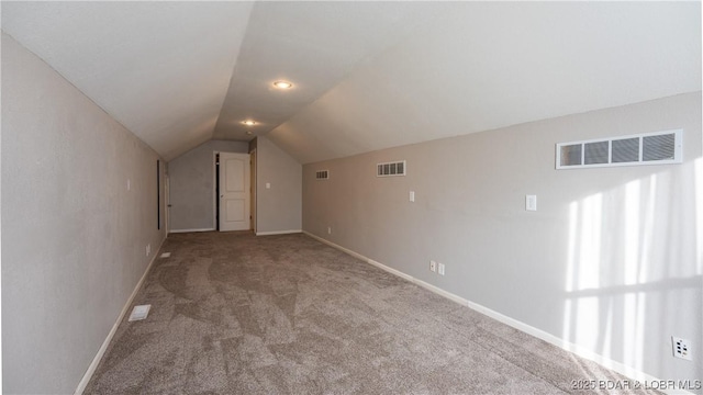 bonus room with light colored carpet and vaulted ceiling