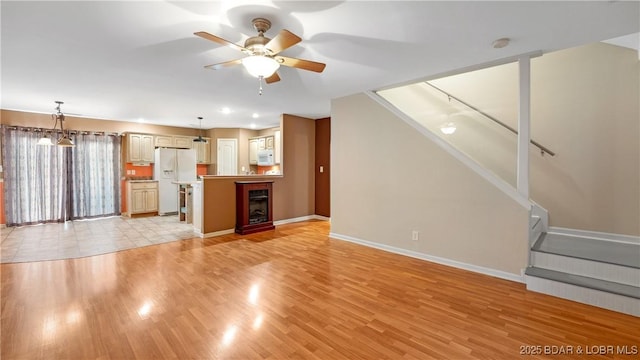 unfurnished living room with ceiling fan with notable chandelier and light hardwood / wood-style flooring