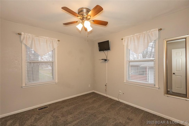 spare room featuring ceiling fan and dark colored carpet