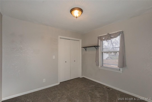 unfurnished bedroom featuring a closet and dark carpet