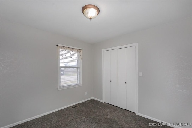 unfurnished bedroom featuring dark carpet and a closet