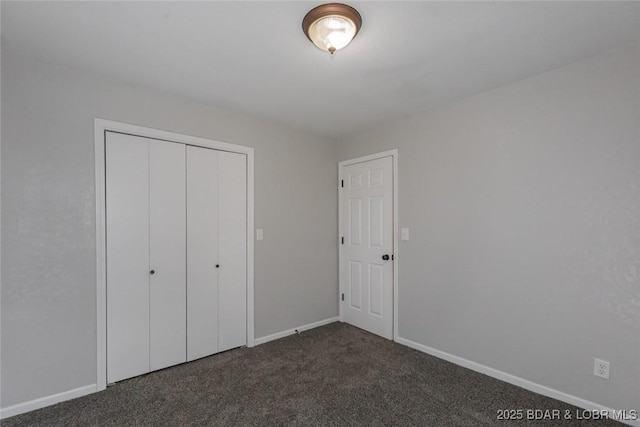 unfurnished bedroom with dark colored carpet and a closet