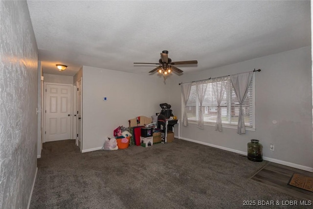 recreation room featuring ceiling fan, a textured ceiling, and dark colored carpet