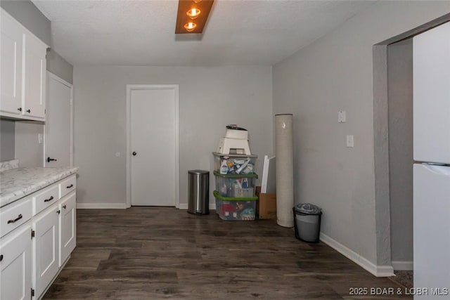 kitchen featuring dark hardwood / wood-style floors, light stone countertops, and white cabinetry