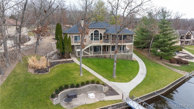 back of property with a balcony and a yard