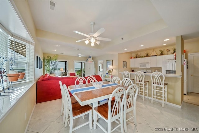 dining area featuring ceiling fan, a healthy amount of sunlight, and a tray ceiling