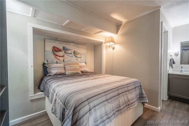 bedroom with a textured ceiling, dark hardwood / wood-style floors, ornamental molding, and connected bathroom