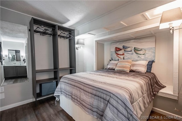 bedroom with a textured ceiling, connected bathroom, and dark hardwood / wood-style flooring