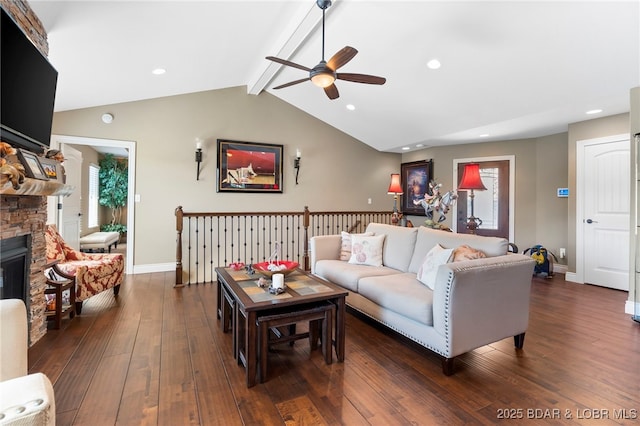 living room with dark wood-type flooring, vaulted ceiling with beams, ceiling fan, a fireplace, and plenty of natural light