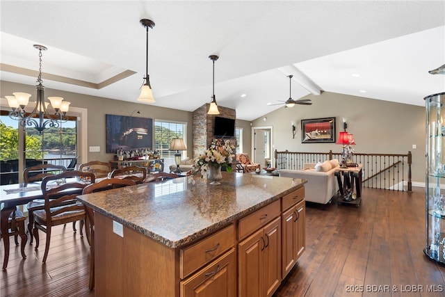 kitchen featuring ceiling fan with notable chandelier, decorative light fixtures, a kitchen island, and dark wood-type flooring