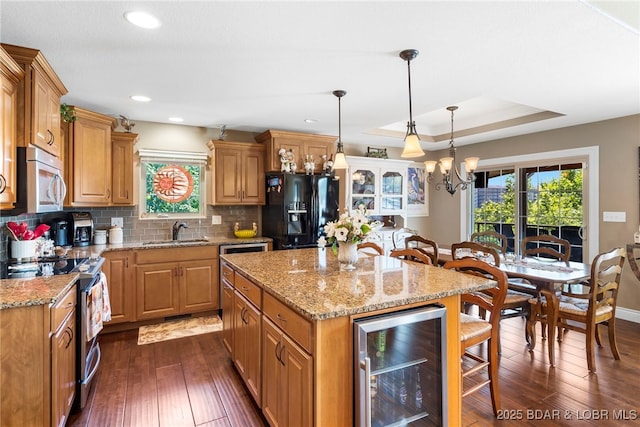 kitchen with a center island, sink, wine cooler, a tray ceiling, and stainless steel appliances