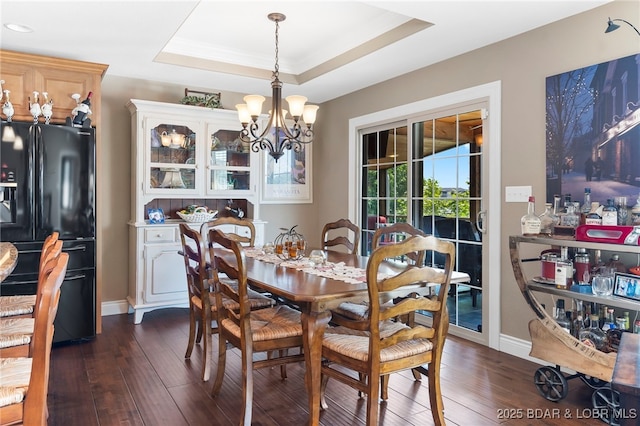 dining area featuring dark hardwood / wood-style flooring, a raised ceiling, and a notable chandelier