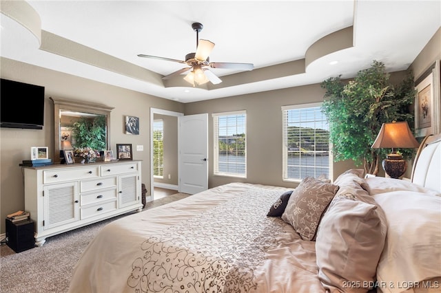 bedroom with carpet floors, a raised ceiling, and ceiling fan