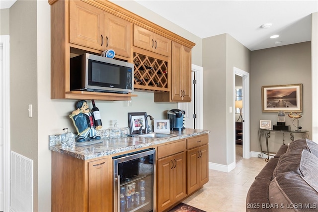 kitchen featuring light tile patterned floors, light stone counters, wine cooler, and sink