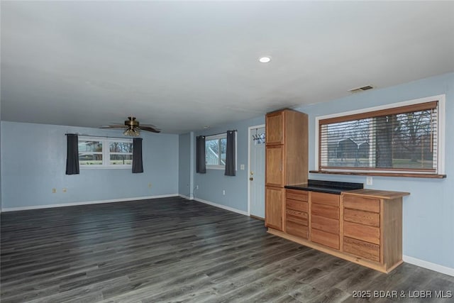 unfurnished living room with a wealth of natural light, ceiling fan, and dark hardwood / wood-style floors