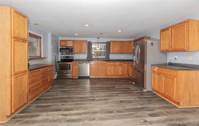 kitchen featuring decorative light fixtures, dark hardwood / wood-style flooring, stainless steel appliances, and sink