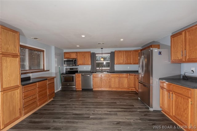 kitchen featuring appliances with stainless steel finishes, dark hardwood / wood-style flooring, hanging light fixtures, and sink