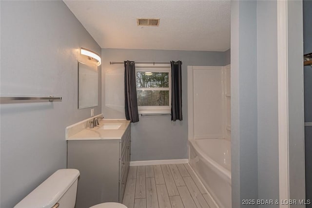 full bathroom featuring vanity, a textured ceiling, wood-type flooring, shower / tub combination, and toilet