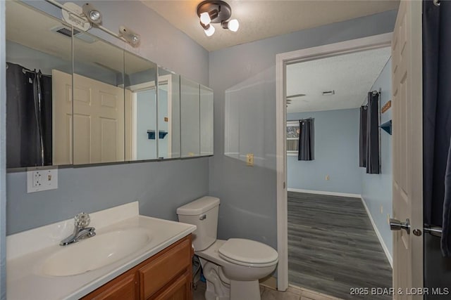 bathroom with a textured ceiling, vanity, hardwood / wood-style flooring, and toilet