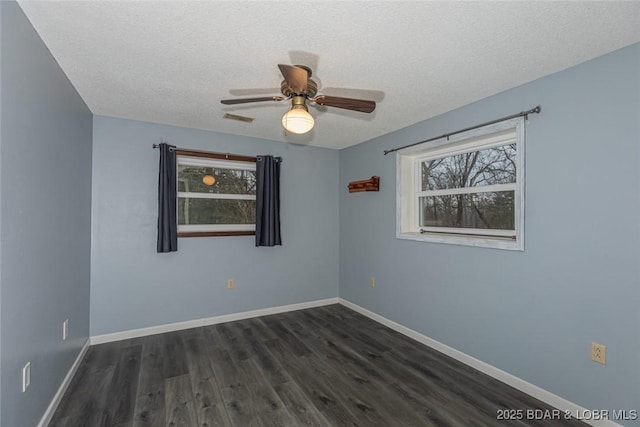 spare room featuring ceiling fan, dark wood-type flooring, and a textured ceiling