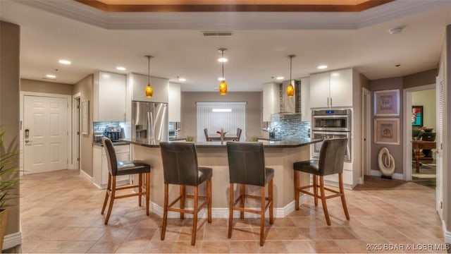 kitchen featuring pendant lighting, backsplash, stainless steel appliances, and wall chimney exhaust hood