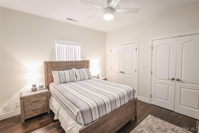 bedroom with ceiling fan, dark hardwood / wood-style flooring, and two closets