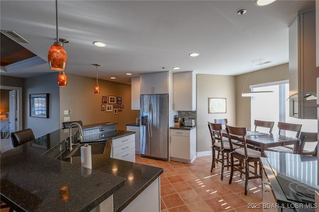 kitchen featuring stainless steel refrigerator with ice dispenser, tasteful backsplash, sink, light tile patterned floors, and pendant lighting