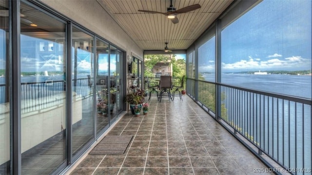 unfurnished sunroom featuring ceiling fan and a water view