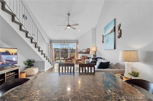 dining space featuring high vaulted ceiling, a ceiling fan, and stairs