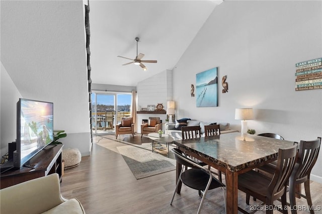 dining space featuring ceiling fan, high vaulted ceiling, and wood finished floors