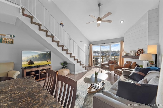 living room with a ceiling fan, stairway, high vaulted ceiling, and wood finished floors