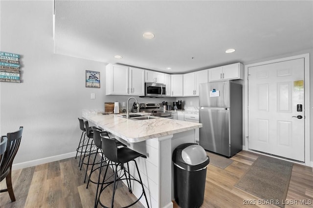 kitchen featuring appliances with stainless steel finishes, white cabinetry, a peninsula, and a kitchen breakfast bar