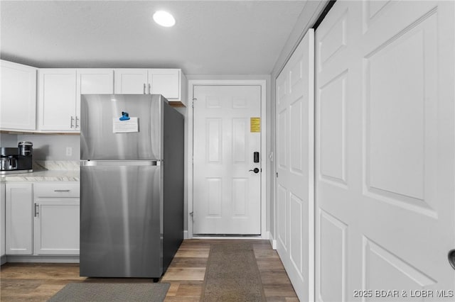 kitchen featuring dark wood-style floors, freestanding refrigerator, white cabinetry, and a textured ceiling