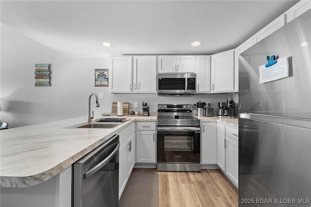 kitchen featuring a peninsula, appliances with stainless steel finishes, a sink, and light countertops