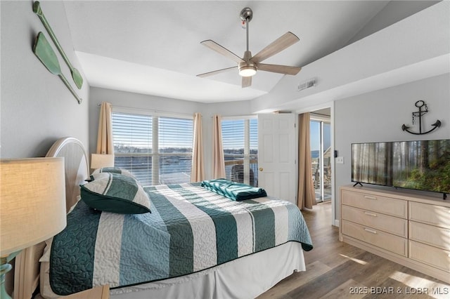 bedroom with a ceiling fan, visible vents, vaulted ceiling, and wood finished floors