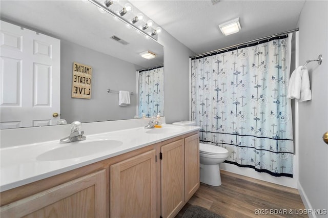 bathroom with wood finished floors, a sink, toilet, and double vanity