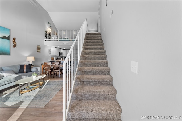 staircase featuring wood finished floors and a towering ceiling