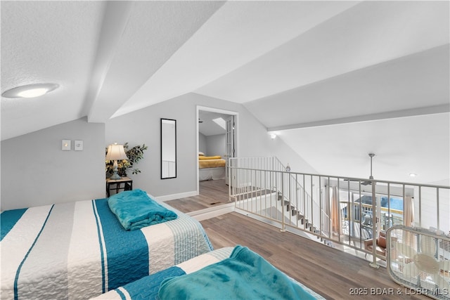 bedroom with vaulted ceiling, a textured ceiling, baseboards, and wood finished floors