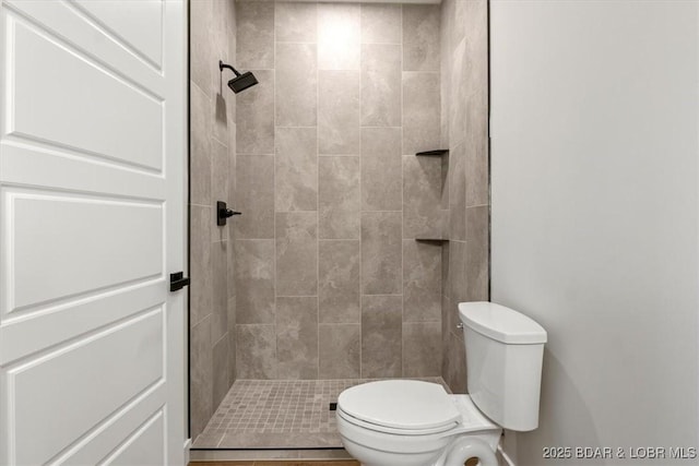 bathroom featuring tiled shower and toilet